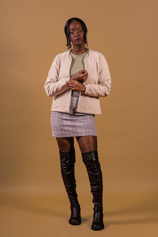 Beije background, model stanting up, lookng at the camera, black boots, short gray skirt, cottom fleece jacket, original 